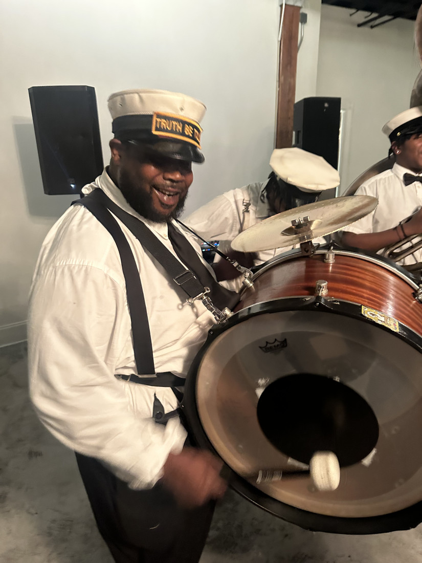 Bass drummer smiling while performing in formal brass band attire
